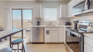 A modern kitchen with white cabinets, stainless steel appliances, and a large window providing a view of the outdoors. - New Studio, Balcony w/views, Nexflix, Pool
 (Albuquerque)