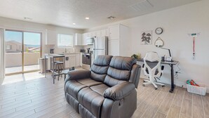 A modern apartment with a living area featuring a leather sofa, a dining table with bar stools, a kitchen with white cabinets, and a balcony with a view. - New Studio, Balcony w/views, Nexflix, Pool
 (Albuquerque)