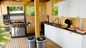 A kitchen with a built-in grill, white cabinets, a sink, and a dish rack. - Immaculate Luxury Fire Island Pines Home, Gourmet Kitchen, Pool, Hot Tub Private (Fire Island Pines)