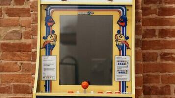 Una máquina de videojuegos Pac-Man fijada en una pared de ladrillos.