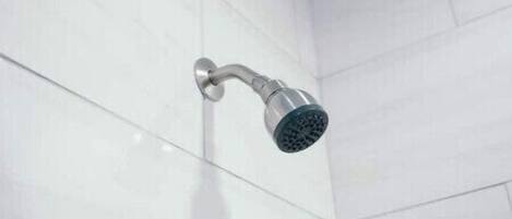 A showerhead mounted on a white tiled wall in a bathroom.