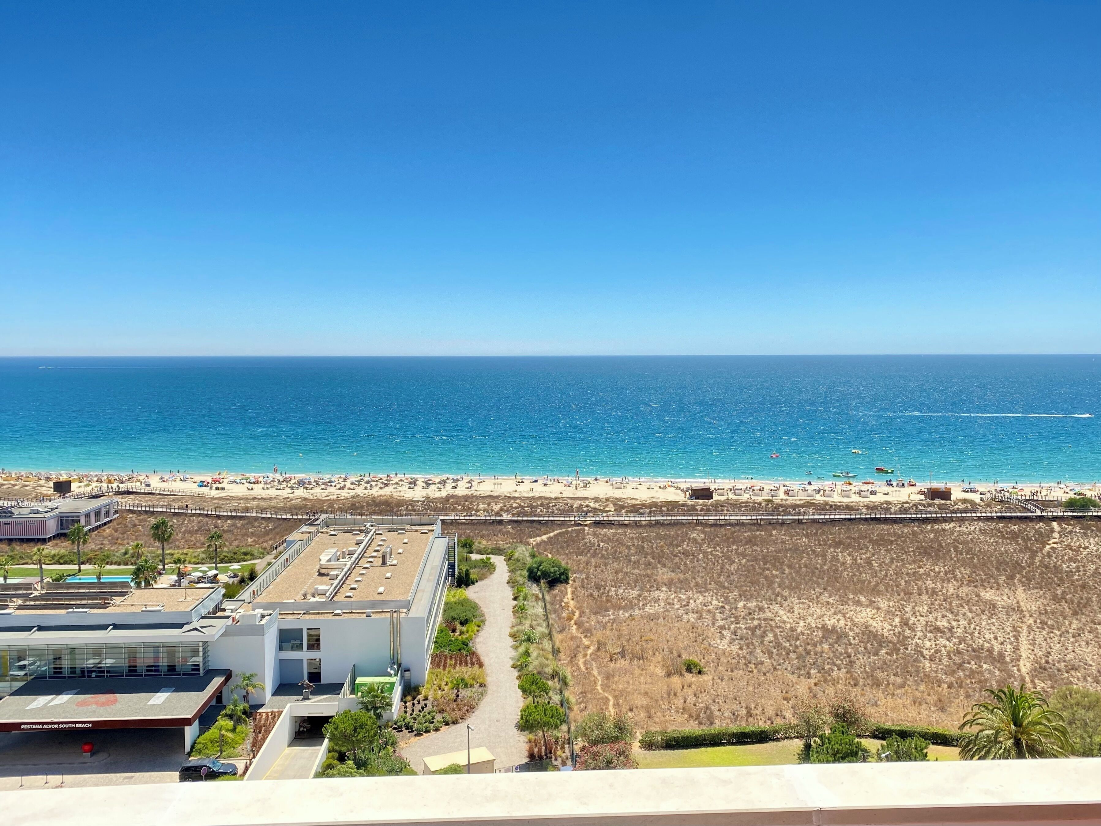A coastal view with a beach, a building labeled "Pestana Alvor South Beach," and a clear sky.