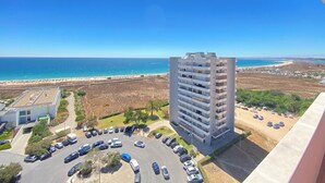 A high-rise building with a view of a beach and parking area.
