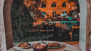 Un área de comedor al aire libre con vista a un edificio histórico a través de un arco.