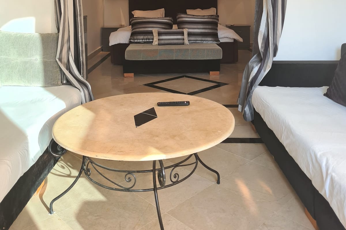 Un dormitorio con una cama, una mesa redonda y un sofá.
