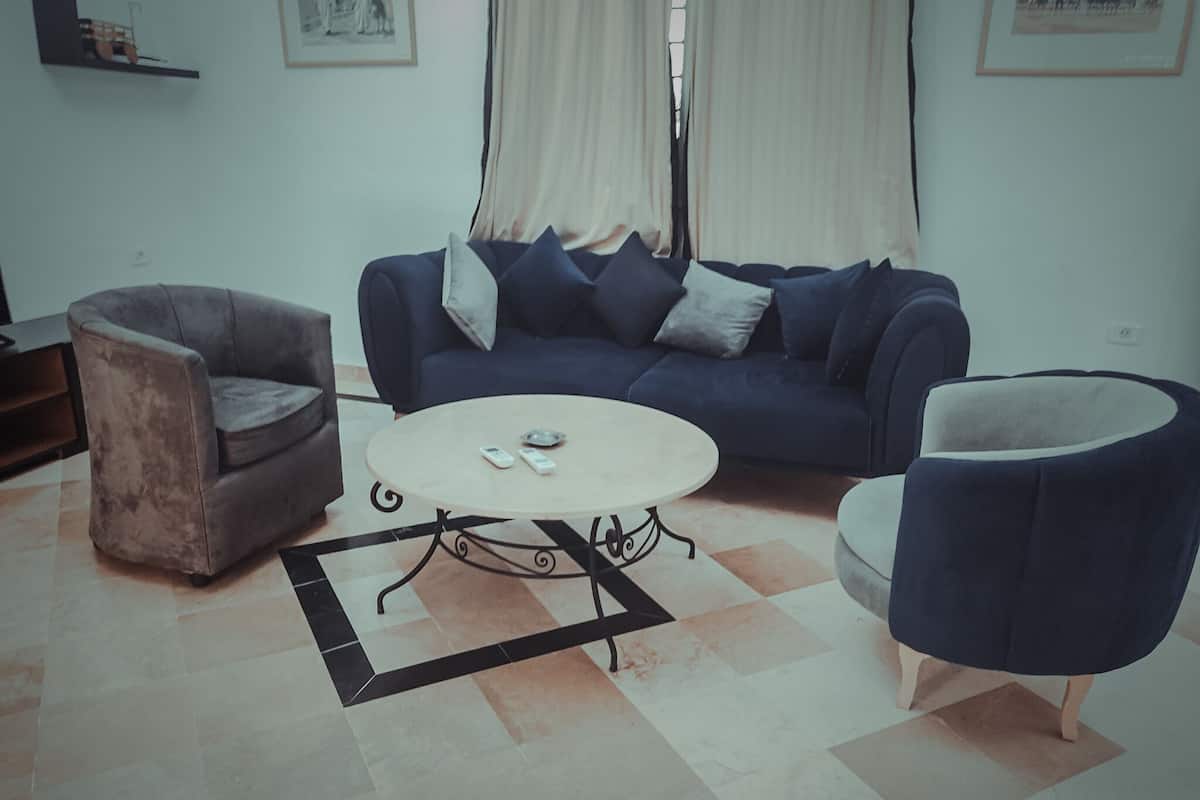 Una sala de estar con un sofá, dos sillones, una mesa de centro y una alfombra.