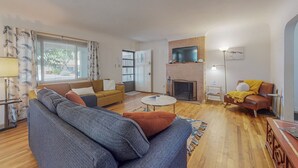 Ein Wohnzimmer mit einer Couch, einem Couchtisch, einem Kamin und einem Fernseher.