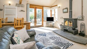 Una sala de estar acogedora con un sofá de cuero, un televisor de pantalla plana, una chimenea y un comedor con muebles de madera.