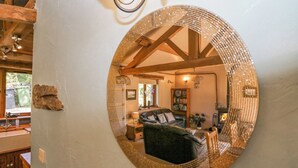 Un espejo circular refleja una sala de estar acogedora con chimenea, estanterías y un sofá de cuero.