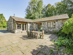 A stone house with a patio and a dining table.
