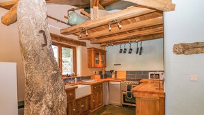 Una cocina rústica con armarios de madera, una encimera de piedra y un colgador para ollas.