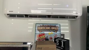 Valkoinen ilmastointilaite, Hurricane Opoly -lautapelin laatikko ja kalenteri, jossa on merkitty päivämäärä 31. maaliskuuta.