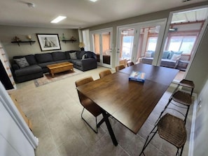 A spacious living area with a dark wooden dining table, a gray sofa, and a coffee table. - Lake Front w/ Sunset Views, Screened-in Porch / 1x Boat Slip / 2x Kayaks (Jasper)