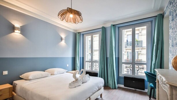 A bedroom with a large bed, two bedside lamps, a window with curtains, and a hanging light fixture. - 3.Appart 6Pers#2 Chambres#Commerce#FullEquipped (Paris)