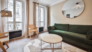 A modern living room with a green sofa, a round mirror, and a small round table. - 3.Appart 6Pers#2 Chambres#Commerce#FullEquipped (Paris)