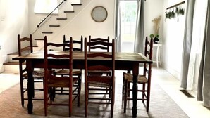 En matplats med ett träbord och stolar, en trappa och ett fönster med gardiner.