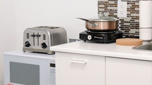 Una cocina con un tostador, una cocedora de arroz y una olla sobre la estufa.