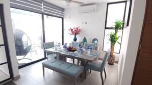 Un comedor con una mesa dispuesta para cuatro personas, un ventilador de techo y una planta en maceta.