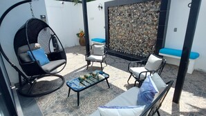 Un espacio de estar al aire libre cubierto con una mecedora, un sofá acolchado y una pequeña mesa con adornos.