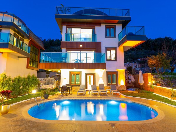 A modern two-story house with a swimming pool, outdoor seating, and a well-lit balcony. - Alanya Luxury Villas  (Antalya)
