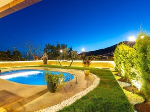 A swimming pool with a tiled deck, surrounded by a well-maintained lawn and a variety of plants. - Alanya Luxury Villas  (Antalya)