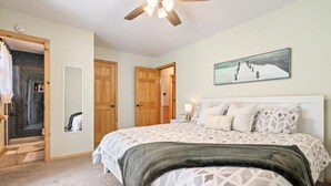 A bedroom with a bed, wooden doors, a ceiling fan, a painting, and a carpeted floor. - Lake House Landing w/ view of sailboat cove, quiet street (Garfield)