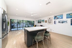 A modern kitchen with a central island, bar stools, and a refrigerator.