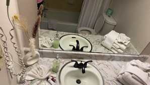Ein Badezimmer mit Marmorwaschbecken, einem Spiegel, einer Toilette und einer Badewanne.
