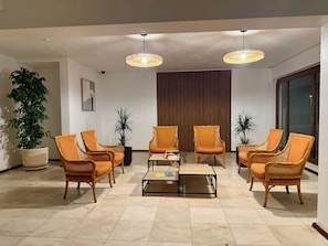 A modern living room with wicker furniture, a coffee table, and potted plants.