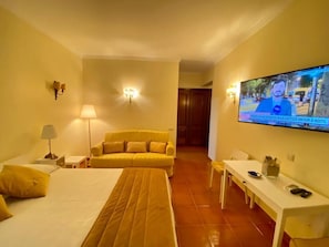 A hotel room with a bed, a sofa, a TV, and a small table.