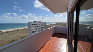 A balcony with a view of the beach and ocean.