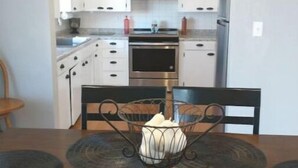 A kitchen with white cabinets, a microwave, and a stove. There is a sign above the entrance that reads "Enter As Strangers - Leave As Friends." - The Jadwin House LLC, Located in Jadwin, Missouri, sleeps 14 guests. (Jadwin)