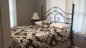 A bedroom with a bed, a ceiling fan, a nightstand, and a lamp. - The Jadwin House LLC, Located in Jadwin, Missouri, sleeps 14 guests. (Jadwin)