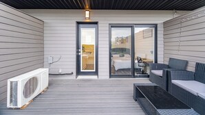 An outdoor patio with a ceiling, a sliding glass door, a white air conditioning unit, and wicker furniture. - Exquisite, bright &modern 2 bedroom condo/Free Parking (Niagara Falls)
