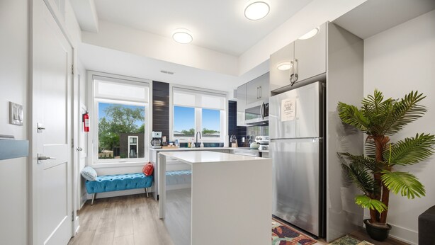 A modern kitchen with a built-in island, a refrigerator, and a potted plant. - Exquisite, bright &modern 2 bedroom condo/Free Parking (Niagara Falls)