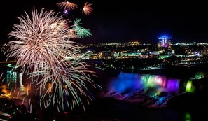 A nighttime cityscape with fireworks and a waterfall.