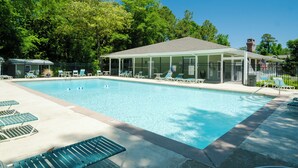 A rectangular swimming pool with a covered pavilion and lounge chairs.
