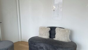 Ett modernt vardagsrum med en grå soffa och ett tillhörande soffbord, en vit dörr och ett vägguttag.