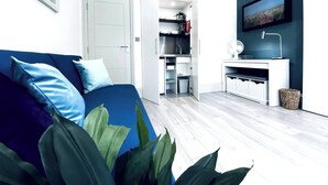 Een moderne woonkamer met een blauwe bank, een witte kast en een groot raam.