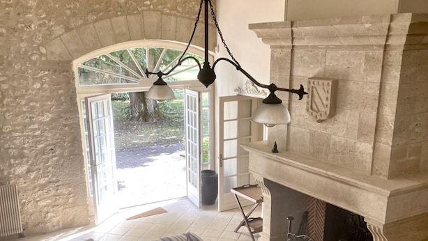 A living room with a stone wall, a fireplace, and a large window.