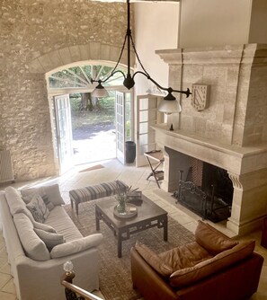 Una sala de estar con pared de piedra, chimenea y un ventanal grande.