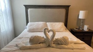 Un lit bien fait, avec une serviette pliée en forme de cœur placée au centre.