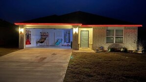 Une maison de plain-pied avec un garage, un porche à l’avant et un petit jardin devant.