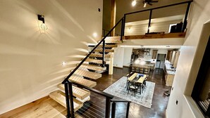 Un intérieur à plusieurs niveaux, avec un escalier en bois, un coin repas et une cuisine.