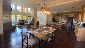 Une cuisine spacieuse avec des meubles en bois, un coin repas doté d’une grande table et de chaises, et une vue sur l’extérieur grâce à de grandes fenêtres.