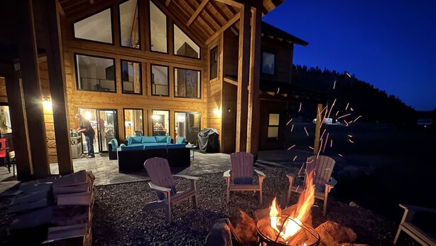 Un chalet en bois doté d’un foyer extérieur et de sièges pour profiter de l’extérieur.