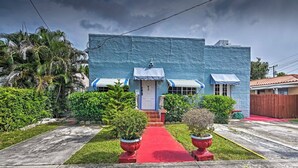 A two-story building with a blue exterior, a front door, and two windows with awnings. There is a red pathway leading to the entrance.