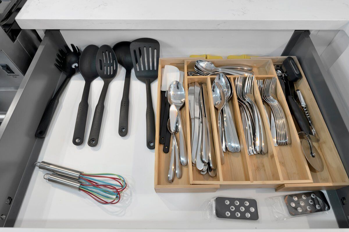 Un tiroir contenant divers ustensiles de cuisine, notamment des spatules, des cuillères, des fourchettes et un fouet.