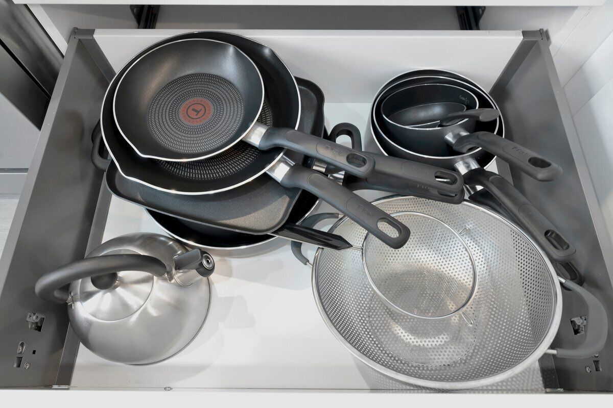Une cuisine équipée d’une cuisinière, d’une poêle, d’une casserole et d’une passoire.