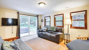 Een gezellige kamer met een leren bank, een flatscreen-tv, een lamp en uitzicht op de omgeving door grote ramen.